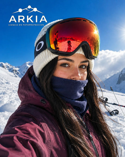 Mujer esquiadora en la nieve con gafas de sol y logo ARKIA - Ciencia en Fotoprotección
